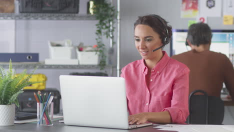 Businesswoman-Wearing-Telephone-Headset-Talking-To-Client-In-Customer-Services-Call-Centre