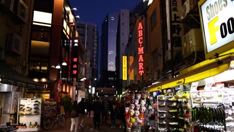 illuminated urban street with pedestrians and shops