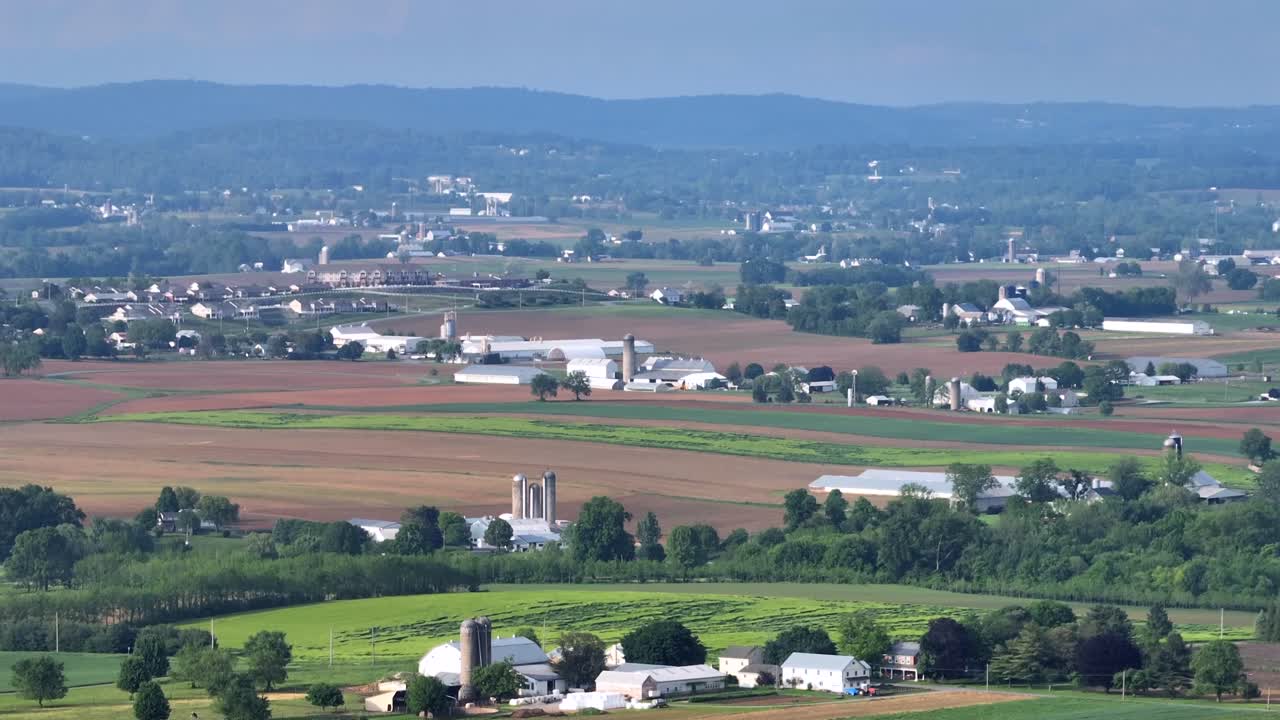 Cloudy day over Rural farm n USA. Barns and silos amidst rolling fields of green crops. Farm buildings and pastures extend into the distance.Rising drone wide shot in spring. PA, United States.