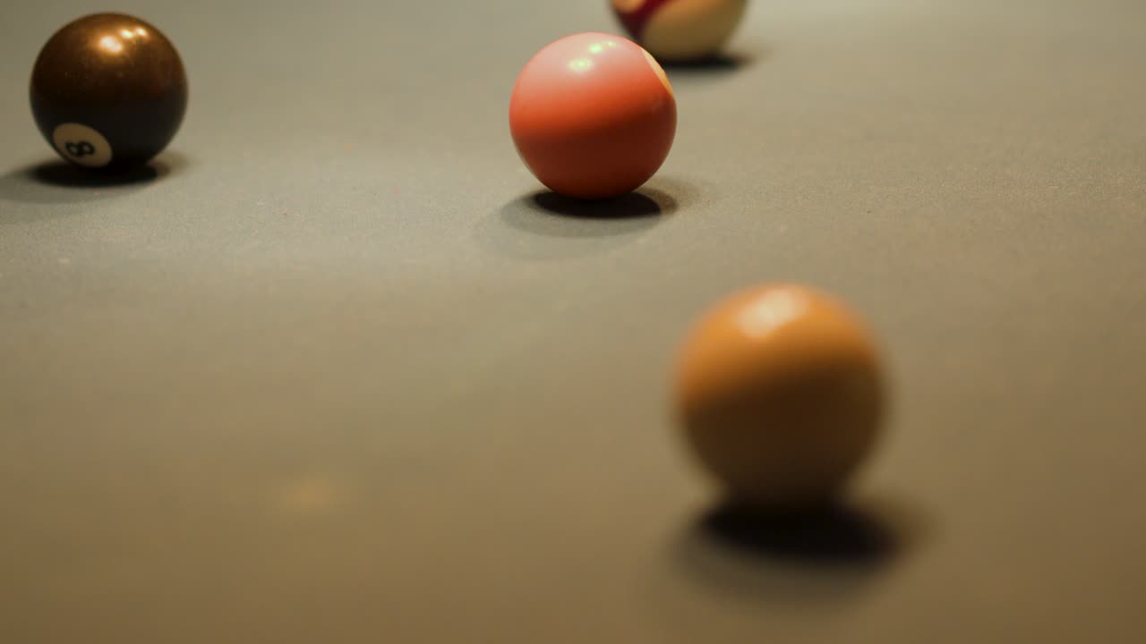Billiard balls move across felt table, warm indoor lighting, shallow focus, smooth camera tracking