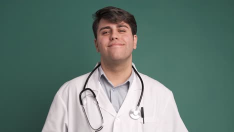happy ethnic young man in white robe medical uniform on green background