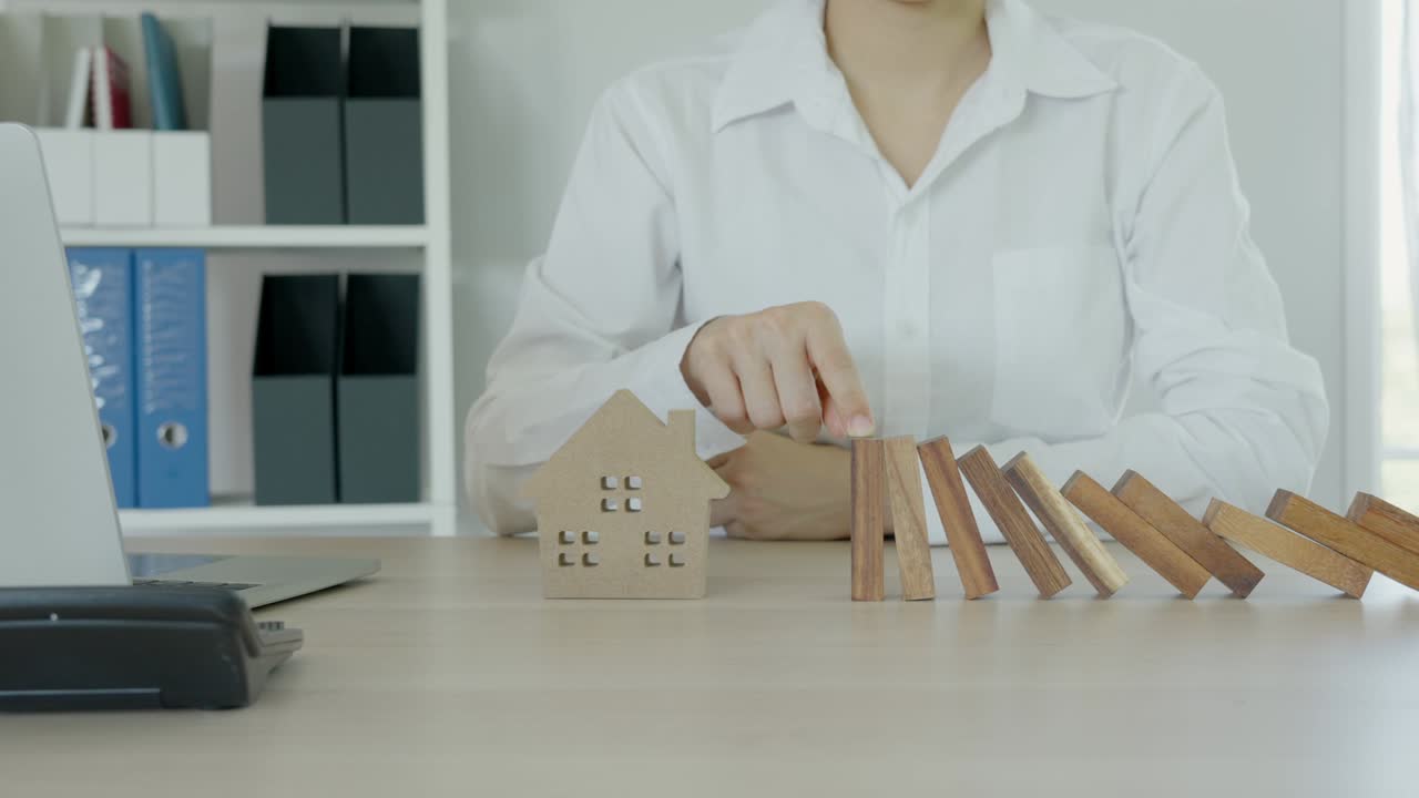 el concepto de seguro de casa o seguro de casa. el rompecabezas de madera está cayendo lentamente y deja de caer a mano. propietario para el concepto de casa nueva.