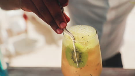 un especialista en cócteles agrega kiwi a una bebida de maracuyá