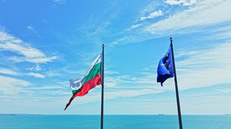 Bandiere della Bulgaria e dell'Unione Europea sventolano nella brezza sopra il mare in una giornata di sole con poche nuvole nel cielo
