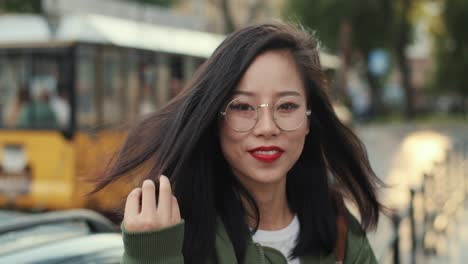 portrait of the female pretty young tourist in glasses smiling happily to the camera with a touristic train on the background