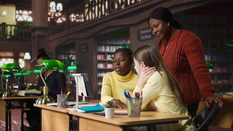 maestro y estudiantes en una biblioteca estudiando en una tableta