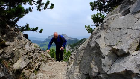 Un-Hombre-Está-Caminando-En-La-Montaña-Con-Una-Hermosa-Montaña-Al-Fondo