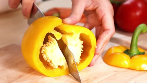 hands cutting yellow peppers on wooden board