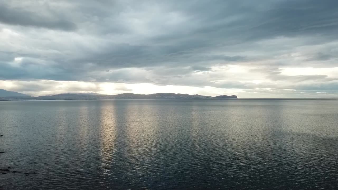 Breathtaking sunset view over the Mediterranean Sea. The golden sun dips below the horizon, casting a warm orange reflection on the calm water