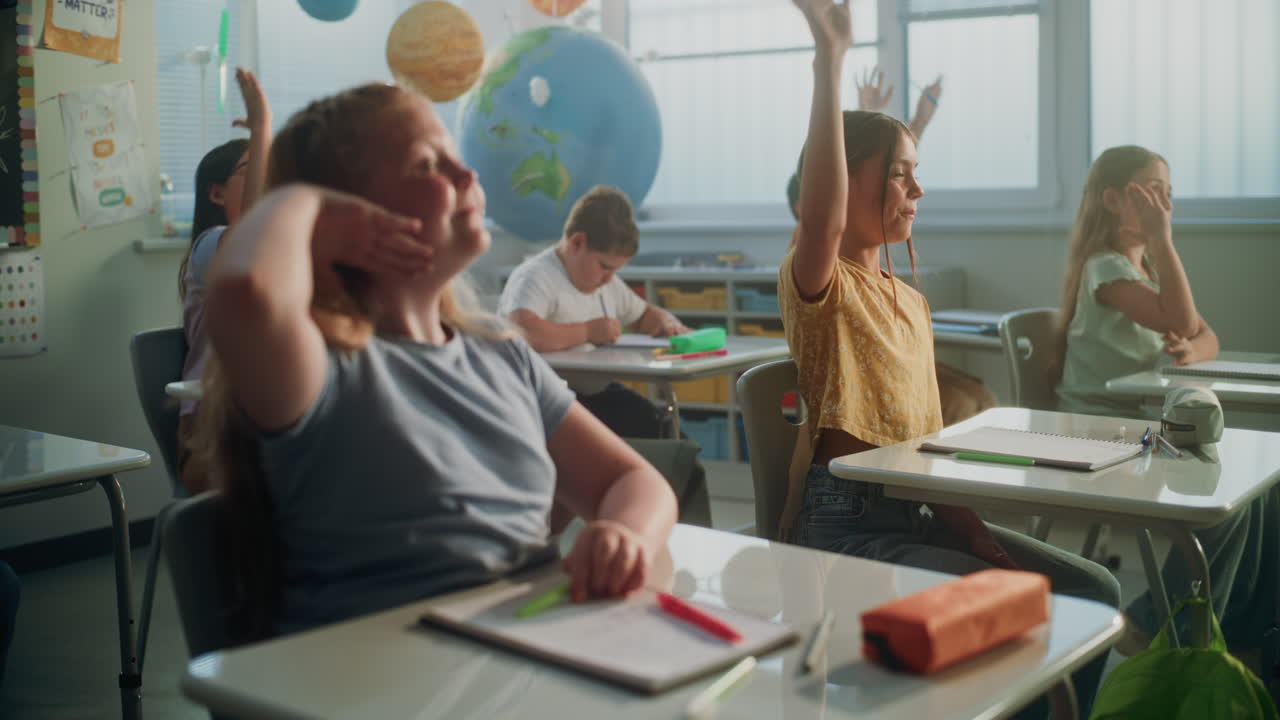 Primary School Children Sitting at Desks Writing School Exam or Doing Tasks in Notebooks