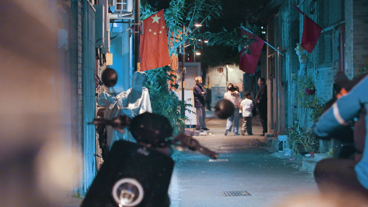 Scooter'lar arasından sıyrılan Asyalı kuryenin olduğu gece sokağı; asılı çamaşırlar, kırmızı fenerler ve mavi neon ışıklar, sinematik bokeh ve bulanıklık; satıcılar ve komşular izliyor, dar alanda gerginlik ve telaş.