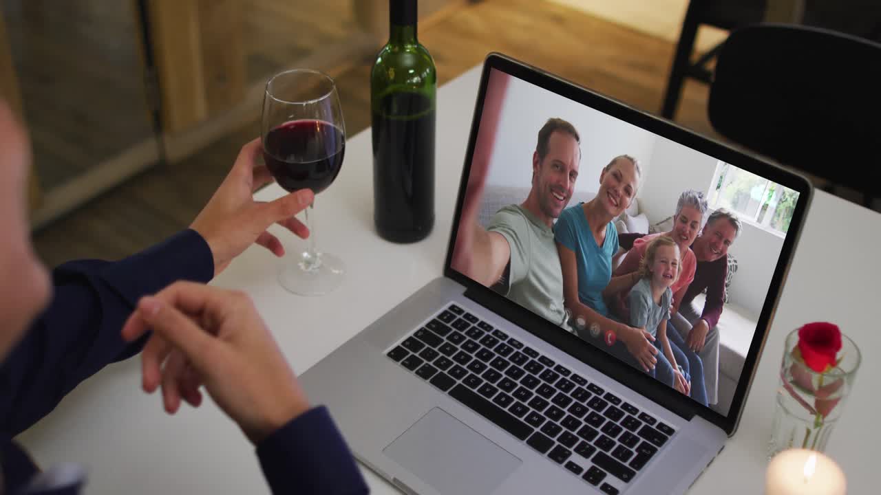 Homem multirracial sentado à mesa usando notebook fazendo chamada de vídeo com a família.