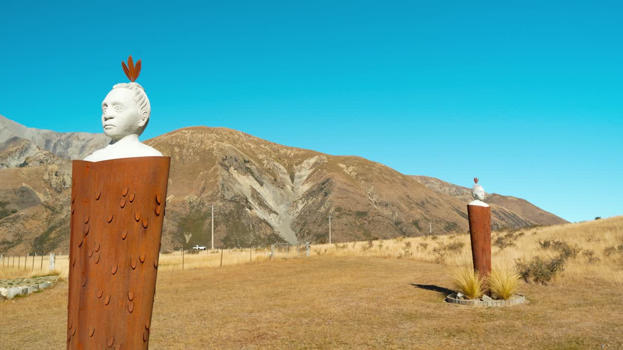 Rightward panning shot reveals the entrance to Castle Hill a.k.a Kura Tāwhiti Conservation Area in New Zealand, featuring carved Māori statues set against the dramatic limestone landscape.