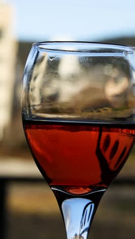 wine glass with red liquid, cityscape in background