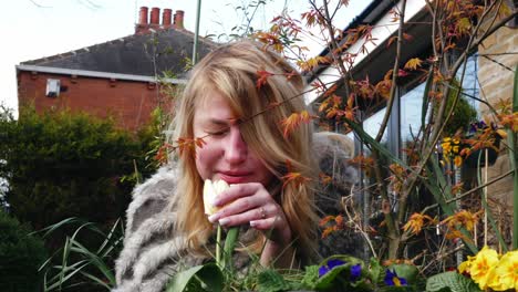 Attractive-woman-enjoying-enjoying-scent-of-flowers-in-garden-medium-shot-slow-motion-portrait