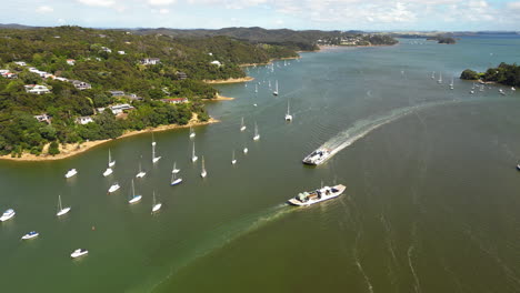 aerial view over bay of islands with anchored sailboats and departing ferry