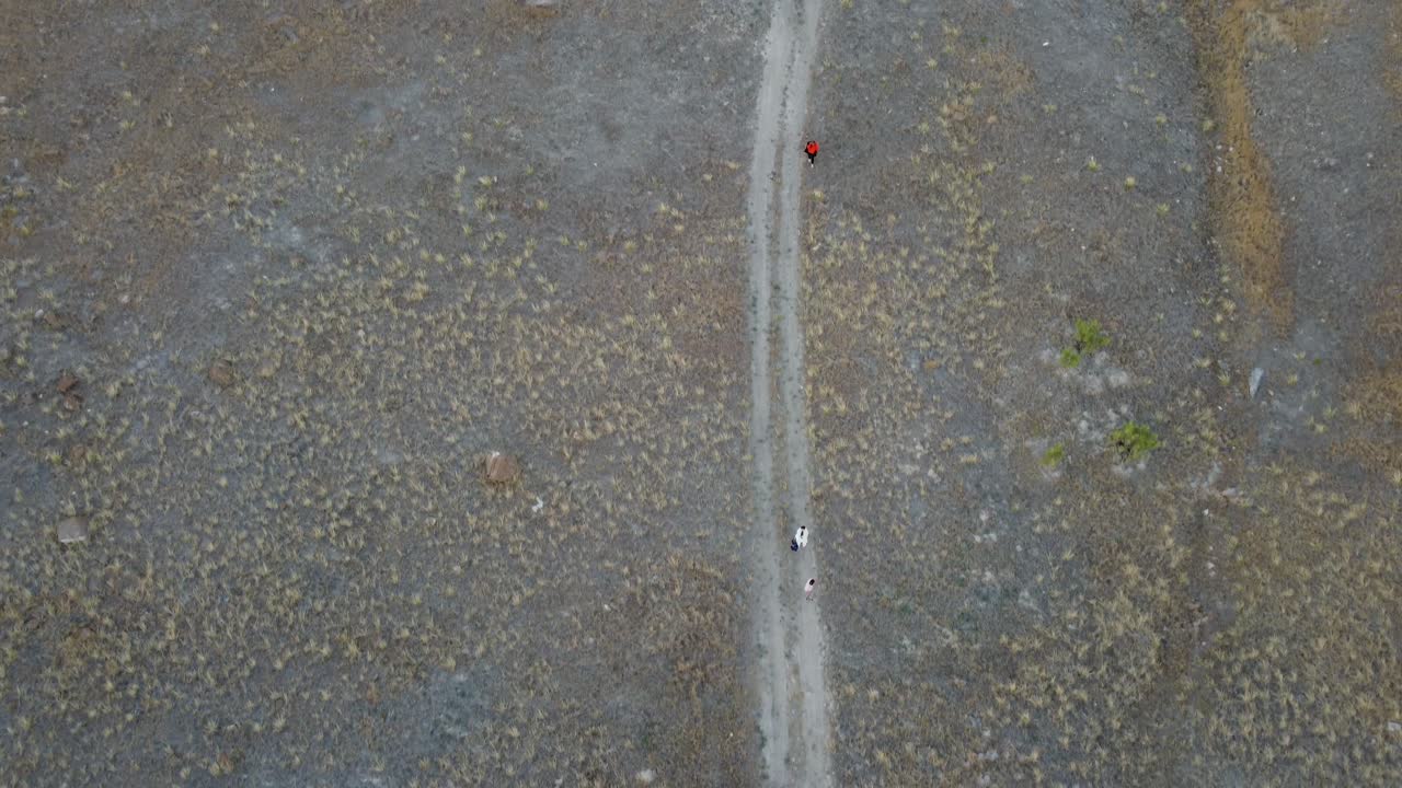 Drone view of a dirt road running through vast Utah desert scenery with mesas in the distance and warm sky tones, creating an atmospheric and adventurous landscape