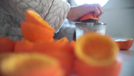 Woman using orange juicer, squeezer, reamer preparing an orange juice at home