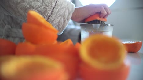 woman using orange juicer, squeezer, reamer preparing an orange juice at home