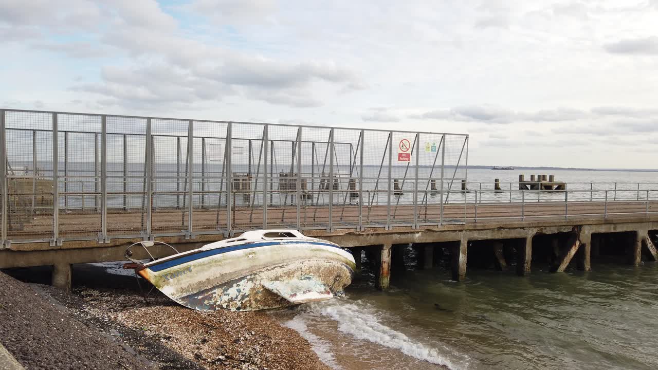 viejo naufragado velero sentando en el lado varado en la playa y contra el embarcadero barcaza pier shoeburyness essex, reino unido