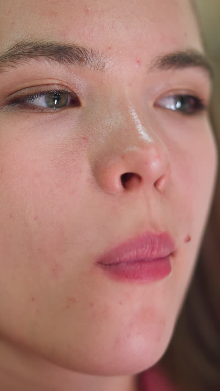 Close-up of a woman enjoying a French fry with a subtle smile on her face with spots on her face , enjoying the delicious taste of the French chops, with blur soft colored light in the background