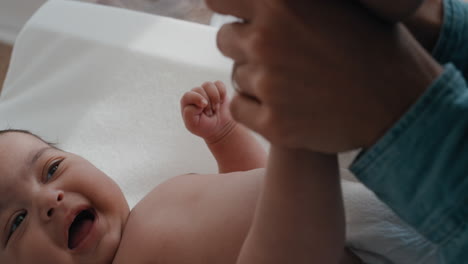 Cerrar-A-Una-Madre-Cuidando-A-Un-Bebé-En-Una-Mesa-Para-Cambiar-Pañales,-Una-Madre-Feliz-Que-Tranquiliza-Juguetonamente-A-Un-Niño-Pequeño-Cuidando-A-Su-Hijo-En-Casa,-Imágenes-De-4k