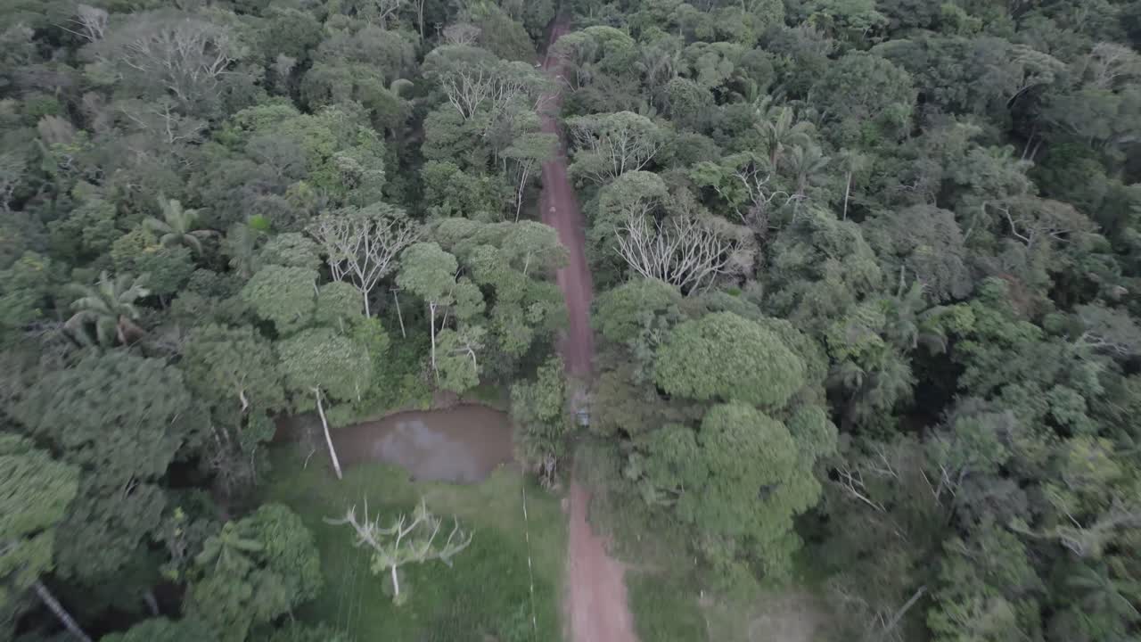 콜롬비아 숲의 비포장 도로에서 운전하는 자동차 - 공중 드론 샷