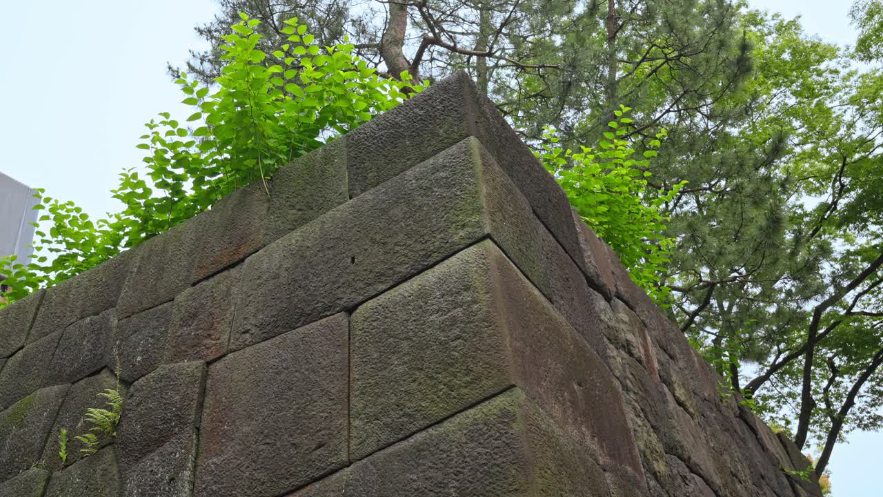A close-up view of a massive stone wall in the Imperial Palace East Garden, showcasing its ancient construction and enduring strength.