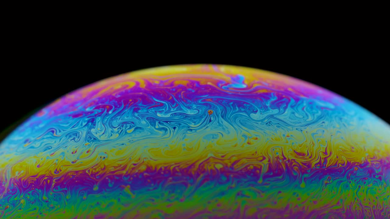 medio círculo una superficie de burbuja de jabón multicolor en movimiento aislado en fondo negro. colores vívidos del arco iris en patrones extraños y extraños. de cerca. cámara lenta