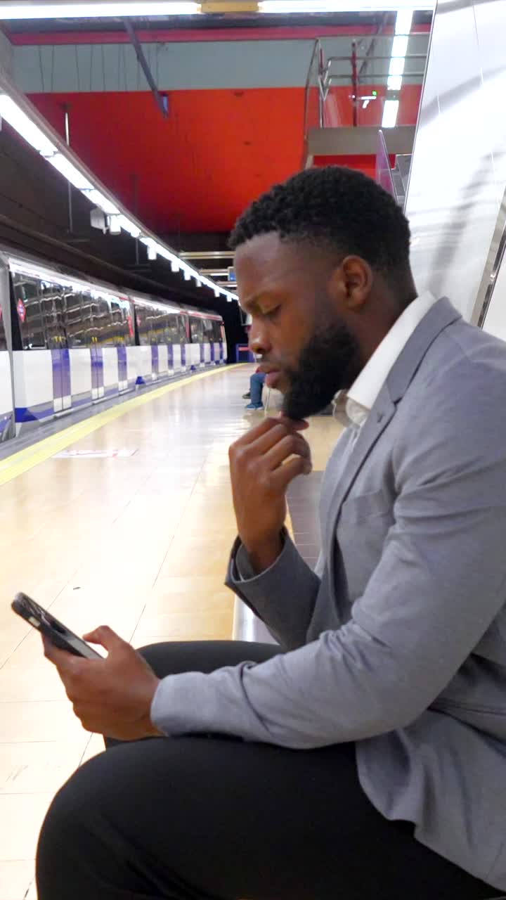 Man waiting at subway platform with phone