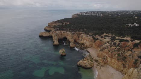 Aerial-view-flying-over-Benagil-caves,-Lagoa,-Algarve-Portugal-with-Atlantic-ocean-transparent-coastline