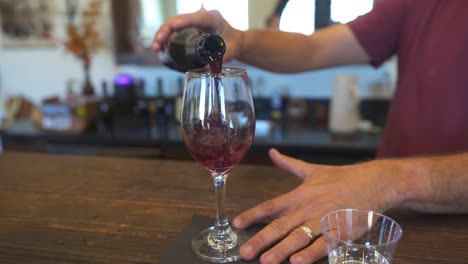 Man-pouring-red-wine-into-glass-during-wine-tasting