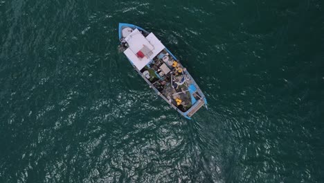 drone circling the fishing boat attached with a skiff from top in the sea adjoining the haifa beach around hof hacarmel