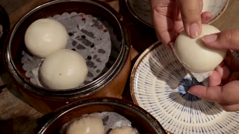 hands opening a steamed bun with filling