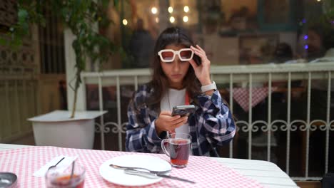 teenager surprised checking phone in outdoor cafe