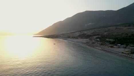 hermosa playa cerca de las montañas con pequeños centros turísticos durante la puesta de sol
