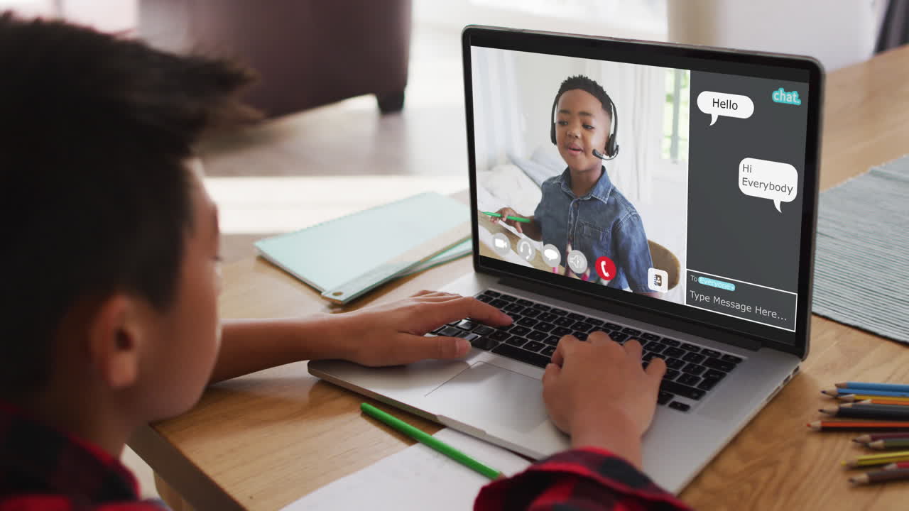 Schoolboy using laptop for online lesson at home, with his colleague and web chat on screen