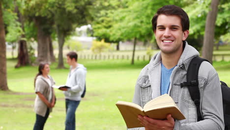 Hombre-Riendo-Mientras-Pasa-La-Página-De-Un-Libro-Antes-De-Mirar-A-La-Cámara