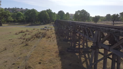 aerial: drone flying low down next to gundagai's historical railway bridge, nsw australia