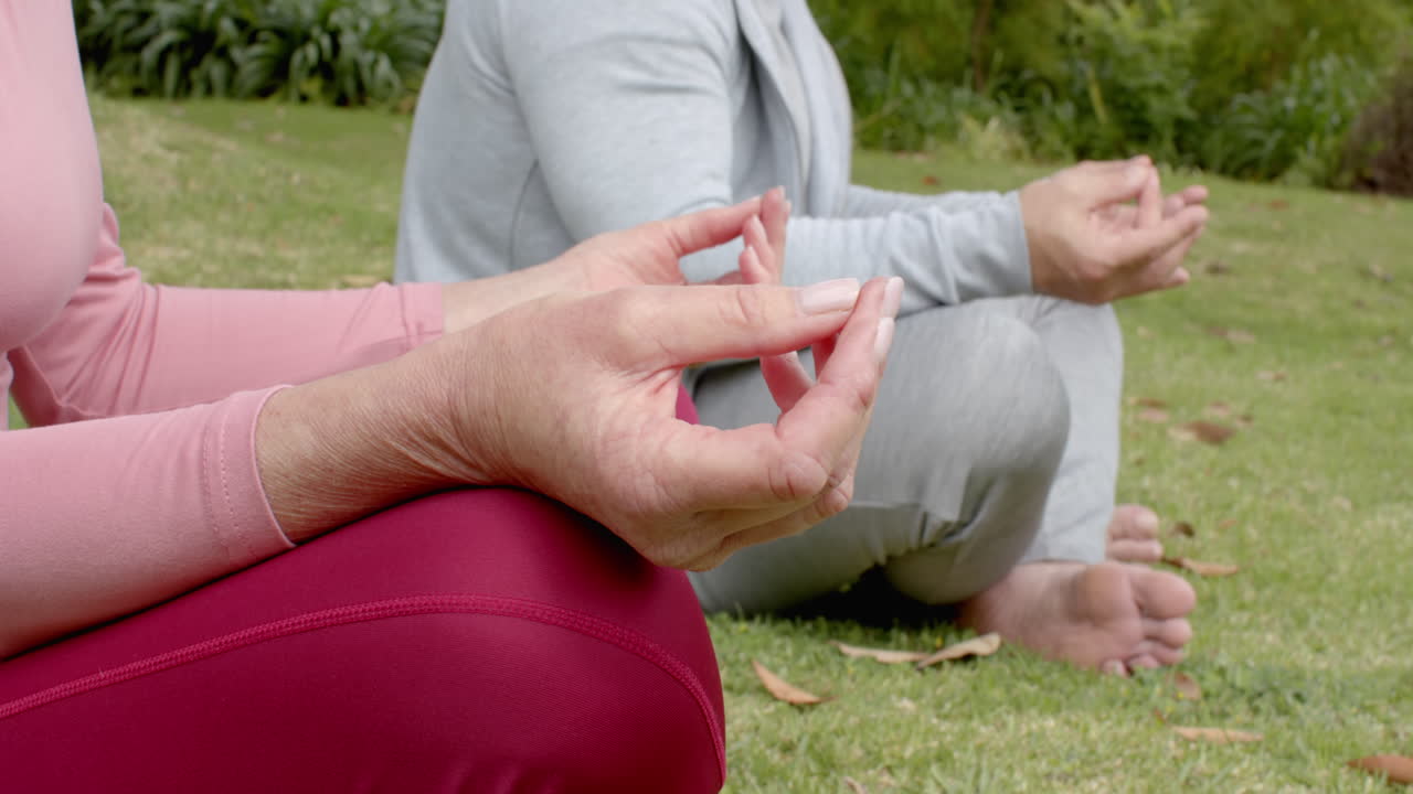 Mature couple meditating outdoors, practicing mindfulness in peaceful garden setting