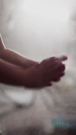 little boy shakes off talcum powder from hands after punching bag against bright lamp illuminating room. toddler finishes boxing class in gym closeup slow motion