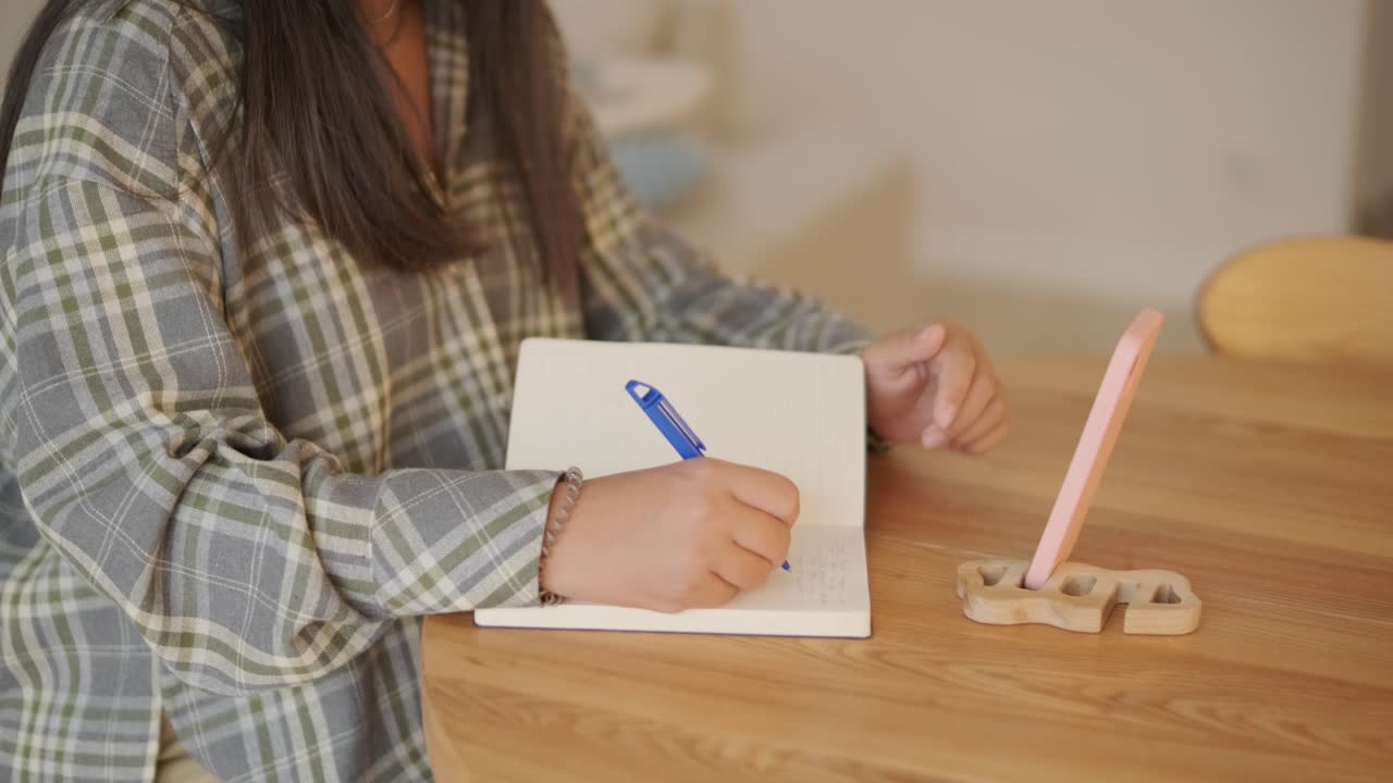 편안하고 부드럽게 조명 된 집 내부에서 나무 테이블에 앉아있는 임신 한 여성, 글쓰기 또는 일기.이 장면은 평온, 집중, 그리고 출산 기간 동안 준비의 감각을 방출합니다.