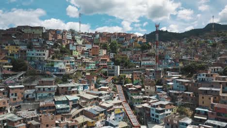 Drone-aerial-landscape-view-of-Comuna-13-slums-touristic-neighborhood,-flying-towards-famous-escalators-in-Medellin,-Colombia