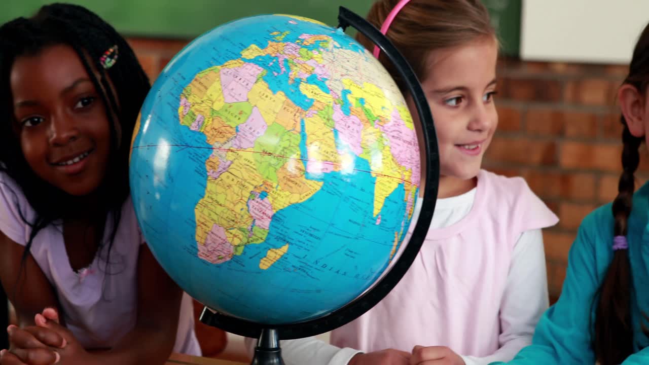 alumnos lindos sonriendo alrededor de un globo en el aula
