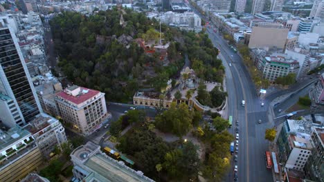 Luftbild-Panoramadrohne-Des-Straßenverkehrs-Von-Santiago-De-Chile,-Des-Städtischen-Grünbereichs-Am-Santa-Lucia-Hügel-Rund-Um-Die-Gebäude-Der-Stadtgegend-Und-Des-Neptunbrunnens