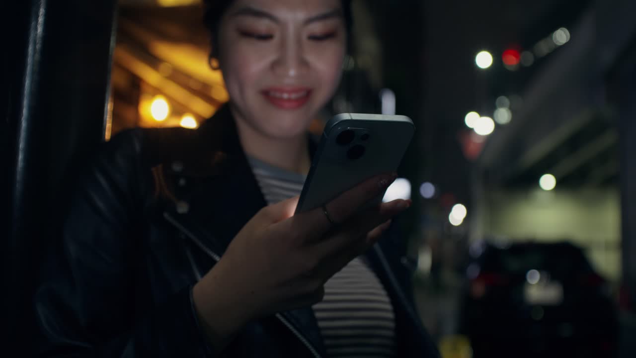 mujer usando teléfono inteligente por la noche en la ciudad