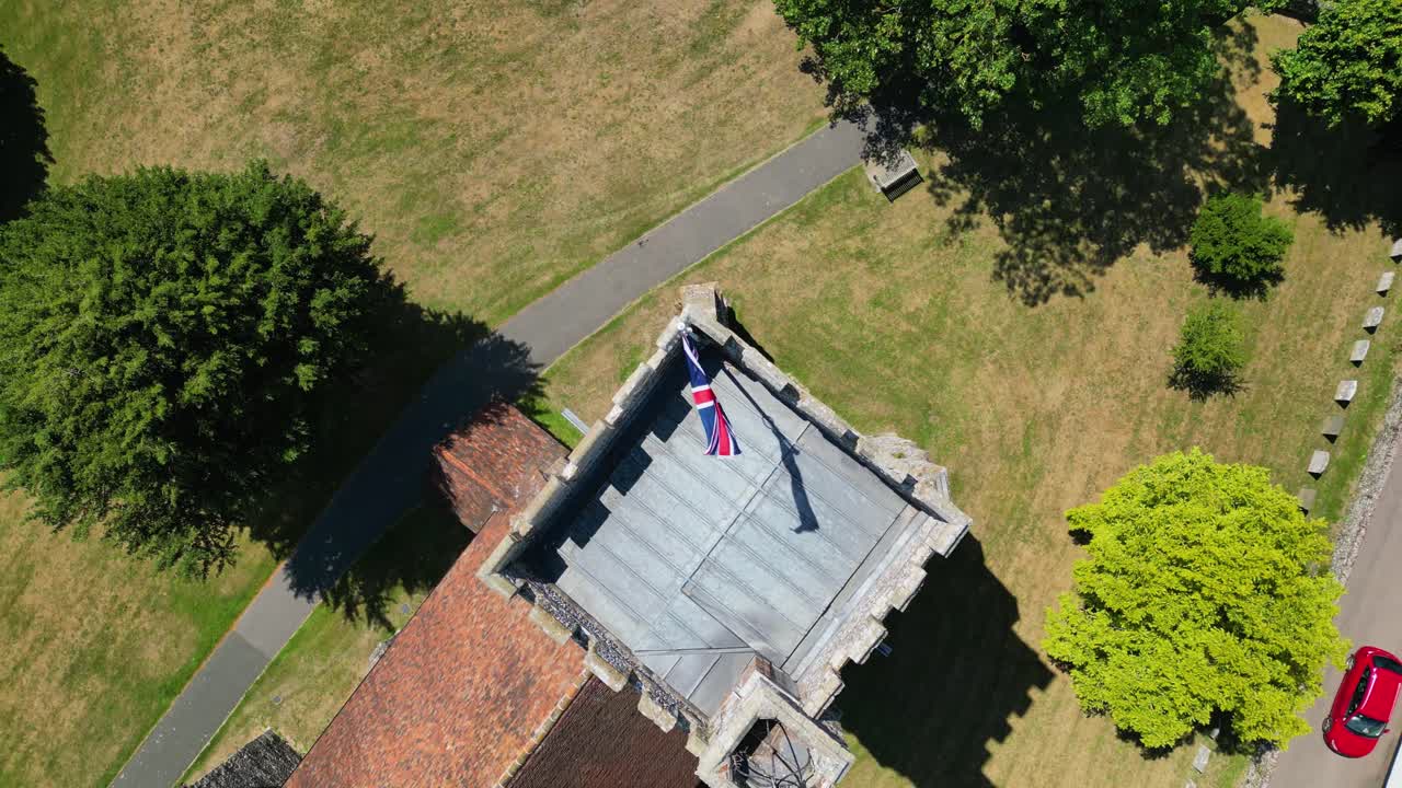 A top-down pan of a union flag flying from the tower of St Mary's church in Chartham