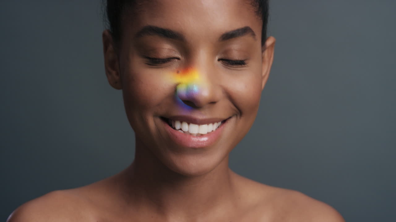 ritratto multicolore bella donna afroamericana con luce colorata che si riflette sulla pelle liscia e sana concetto attraente di cura della pelle femminile su sfondo grigio