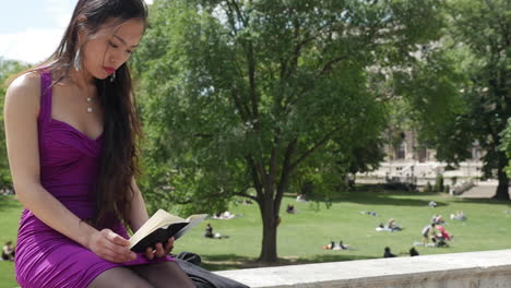 Chica-Asiática-Sentada-En-El-Parapeto-En-Viena,-Leyendo---Cámara-Lenta