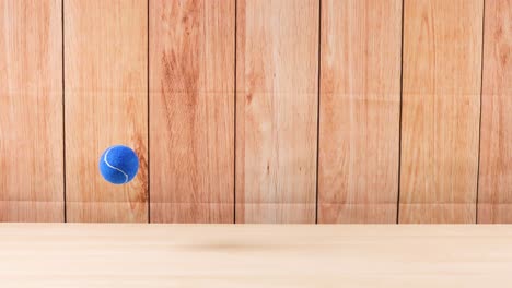 una pelota de tenis azul rebota contra una pared de madera